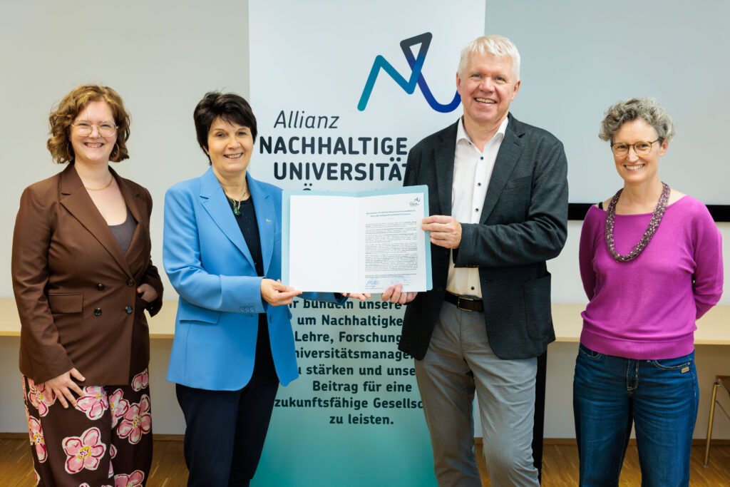 Allianz-Koordinatorin Beringer, BOKU-Rektorin Schulev-Steindl, MUI-Rektor Mayer und Sprecher*in der Expert*innengruppe Bohunovsky vor dem Banner der Allianz bei der Unterzeichnung des Memorandums of Understanding zum Beitritt der MUI.